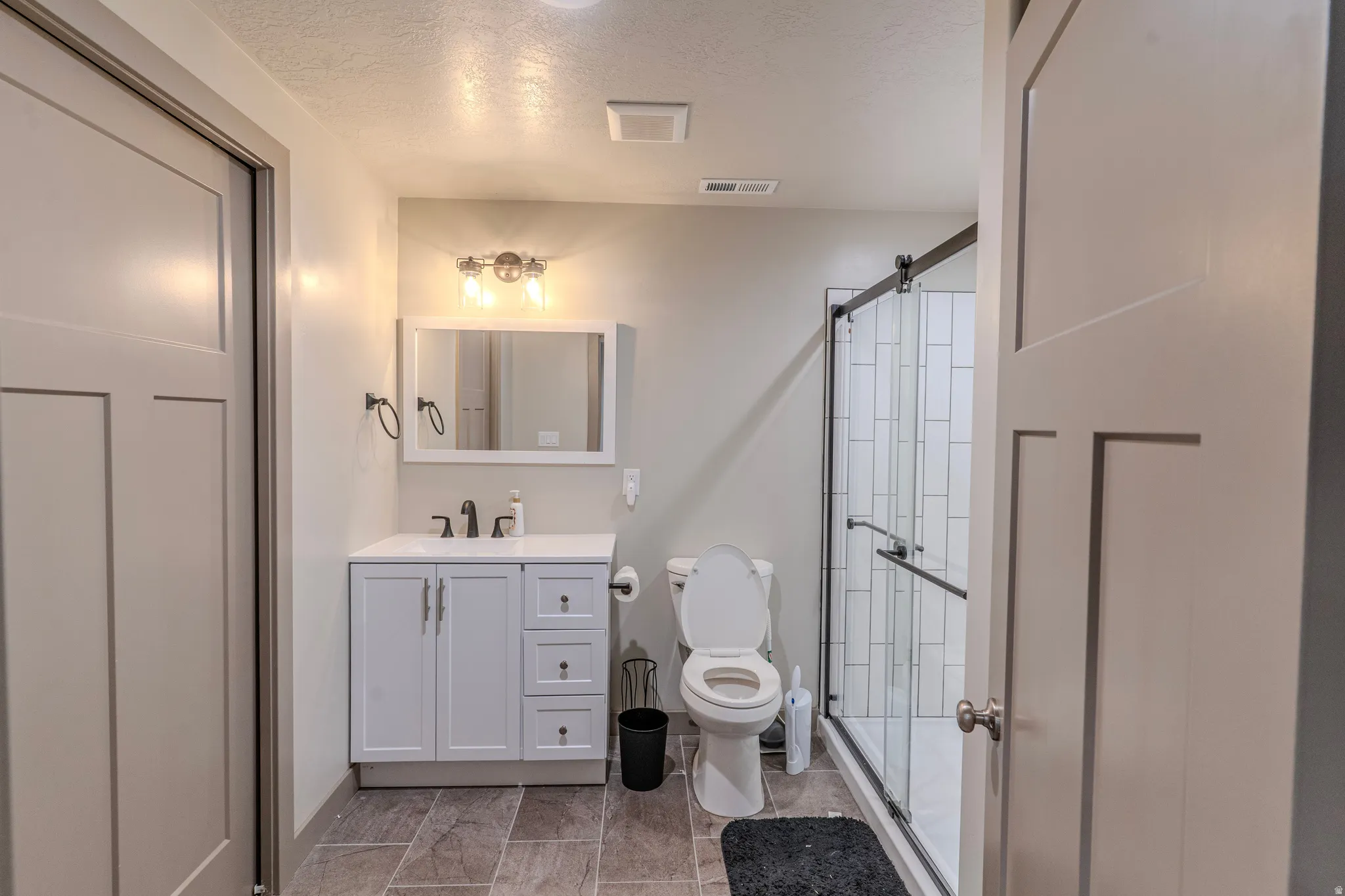 Contemporary bathroom featuring a white vanity with a rectangular sink, a framed mirror, and a three-light vanity fixture