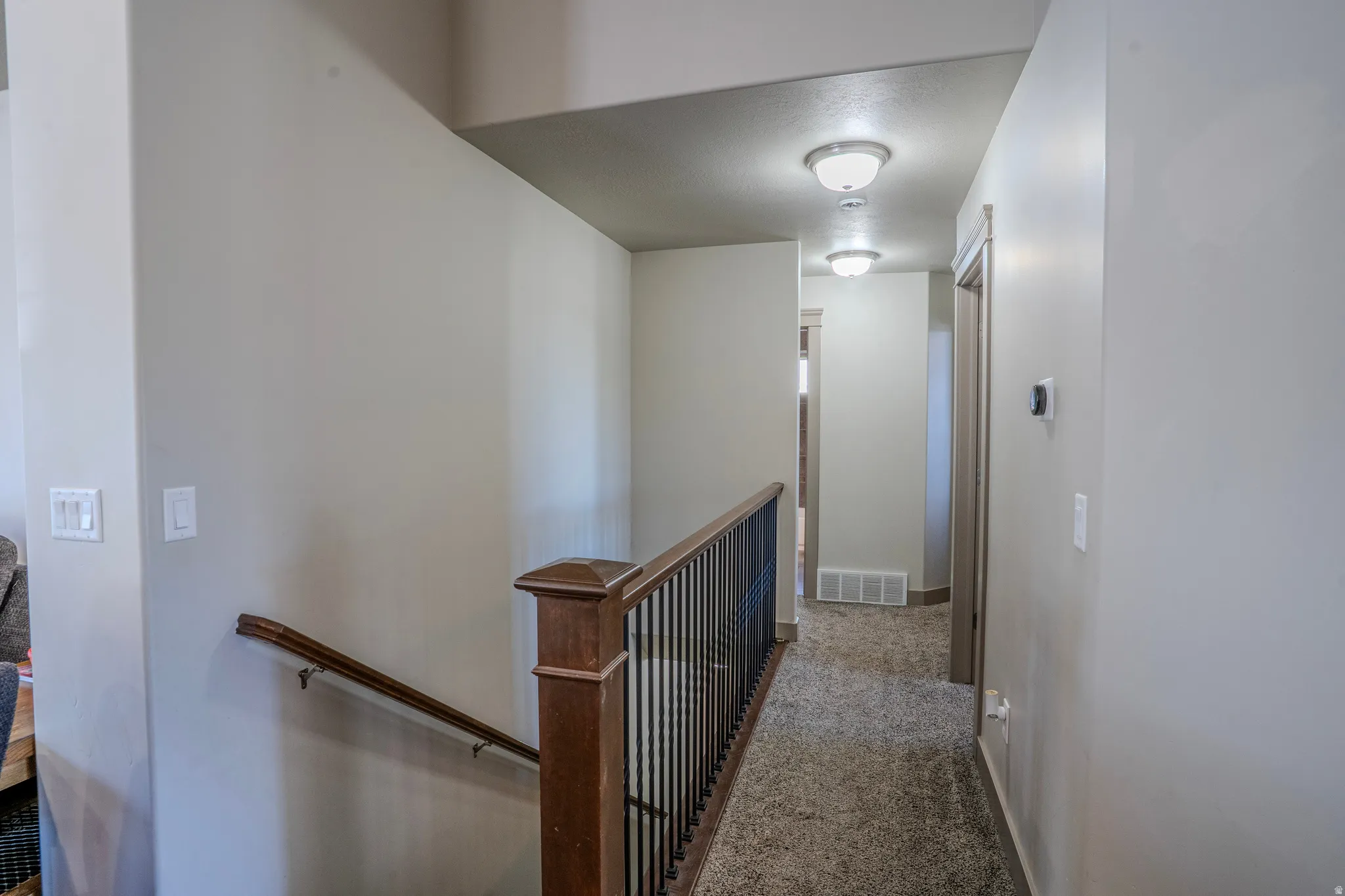 Hallway featuring textured carpeting and flush-mount ceiling lights