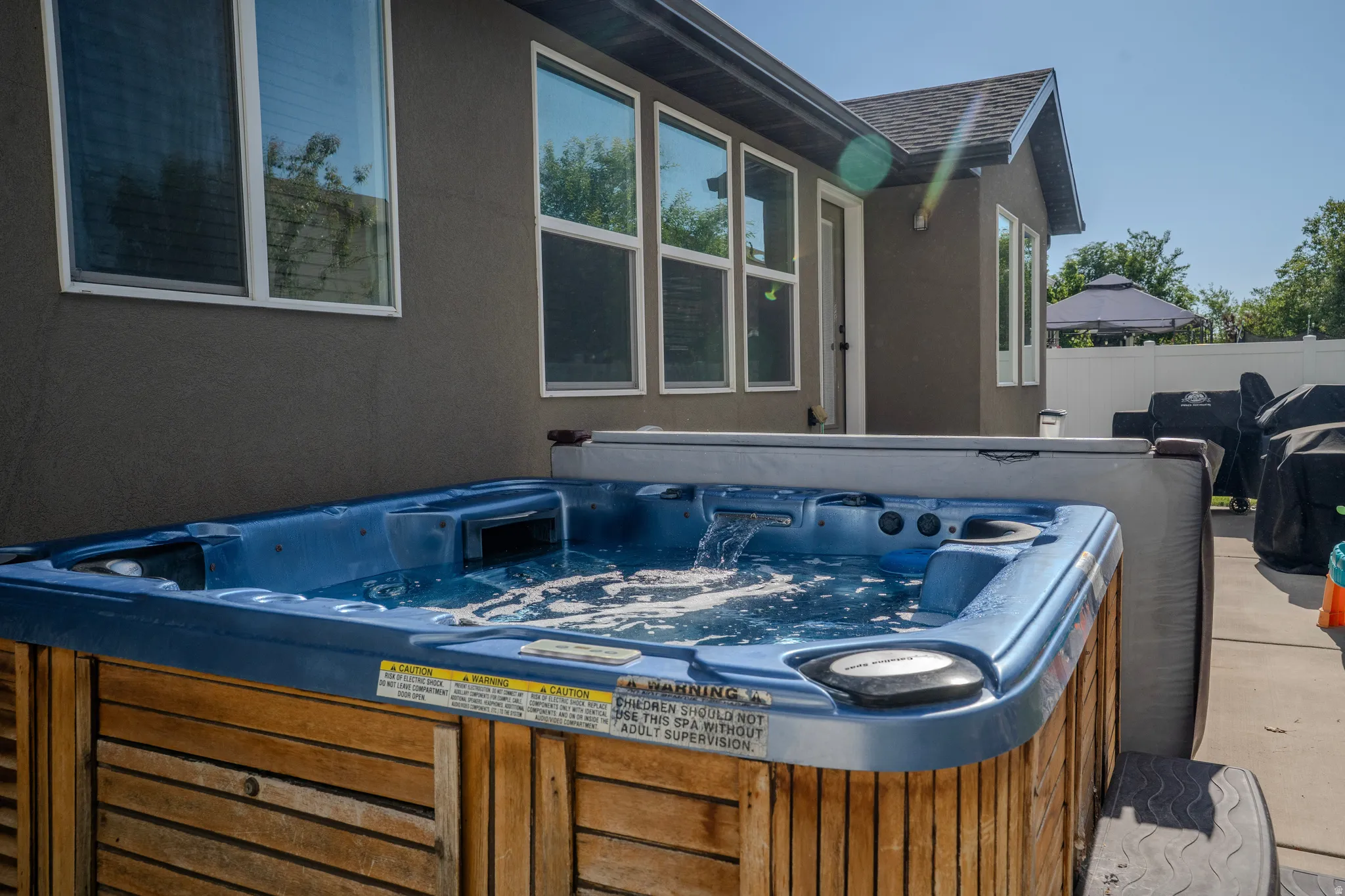 Outdoor spa with a wood-finish exterior, bubbling water, and a hard cover