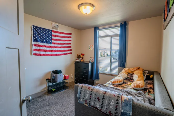 Carpeted room with a double-pane window, horizontal blinds, and blue curtains
