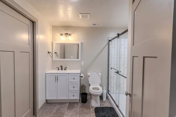 Contemporary bathroom featuring a white vanity with a rectangular sink, a framed mirror, and a three-light vanity fixture