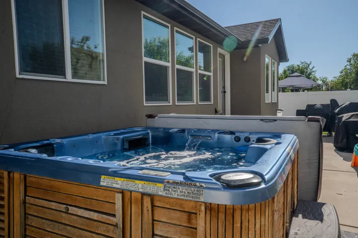 Outdoor spa with a wood-finish exterior, bubbling water, and a hard cover