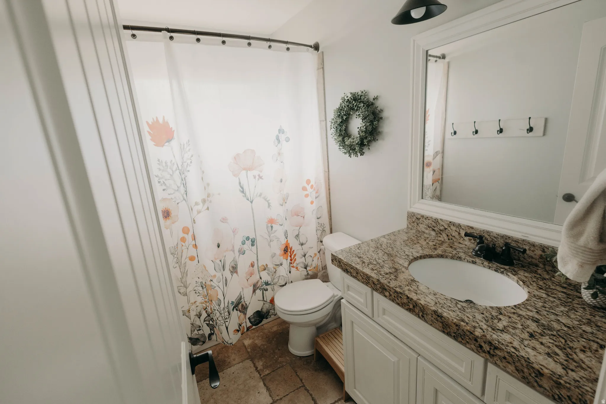Bathroom featuring a granite countertop vanity with an undermount sink, a framed mirror, and a built-in toilet