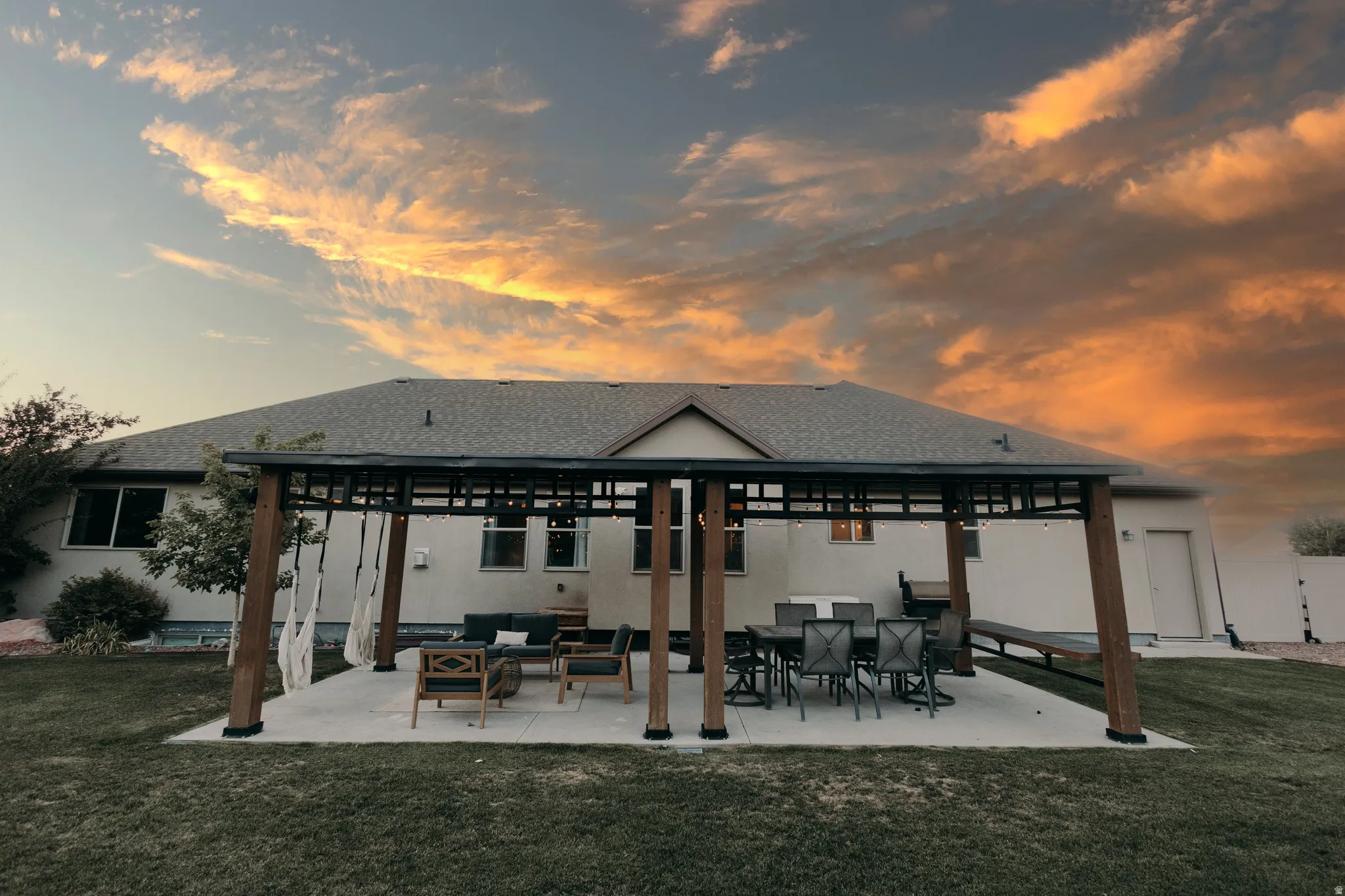 Expansive backyard featuring a covered patio structure on a concrete slab