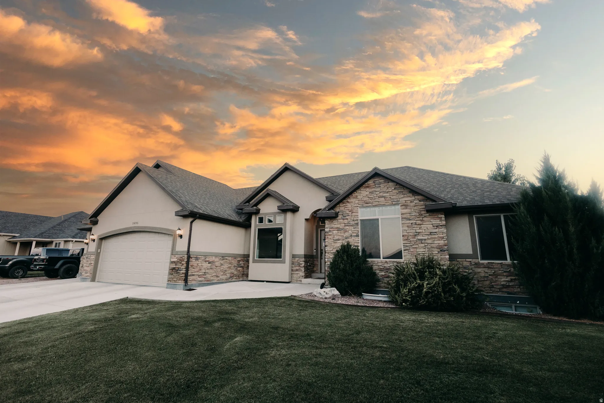 Single-story residence featuring a stone and stucco exterior, an attached two-car garage, and a concrete driveway