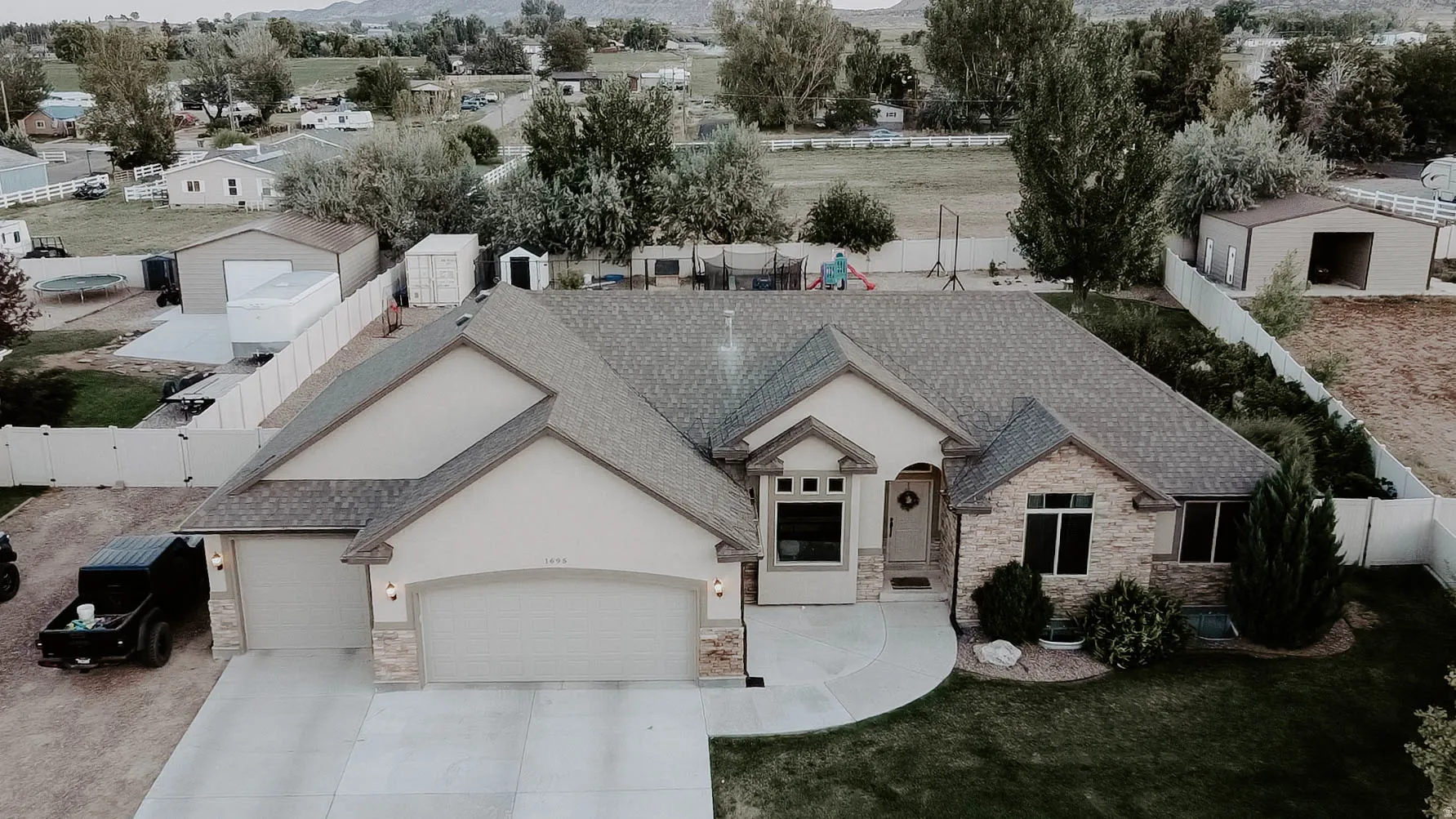 Ranch-style residence featuring a stone and stucco exterior, a two-car garage, and a semicircular concrete walkway