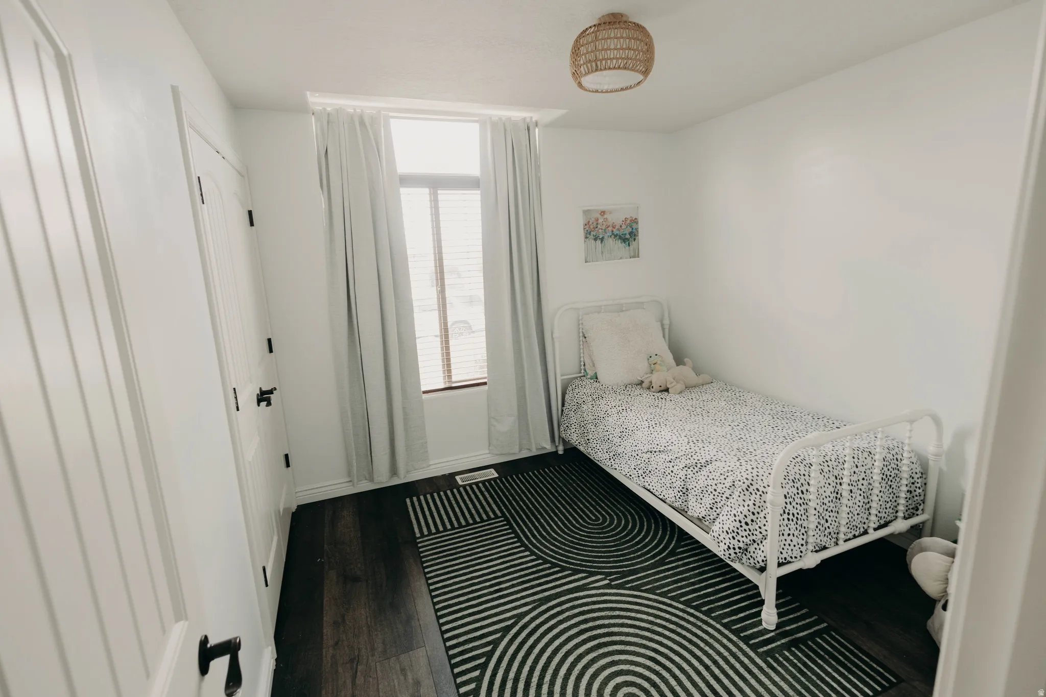 Bright room with dark wood-finish flooring, white walls, and a single window with blinds