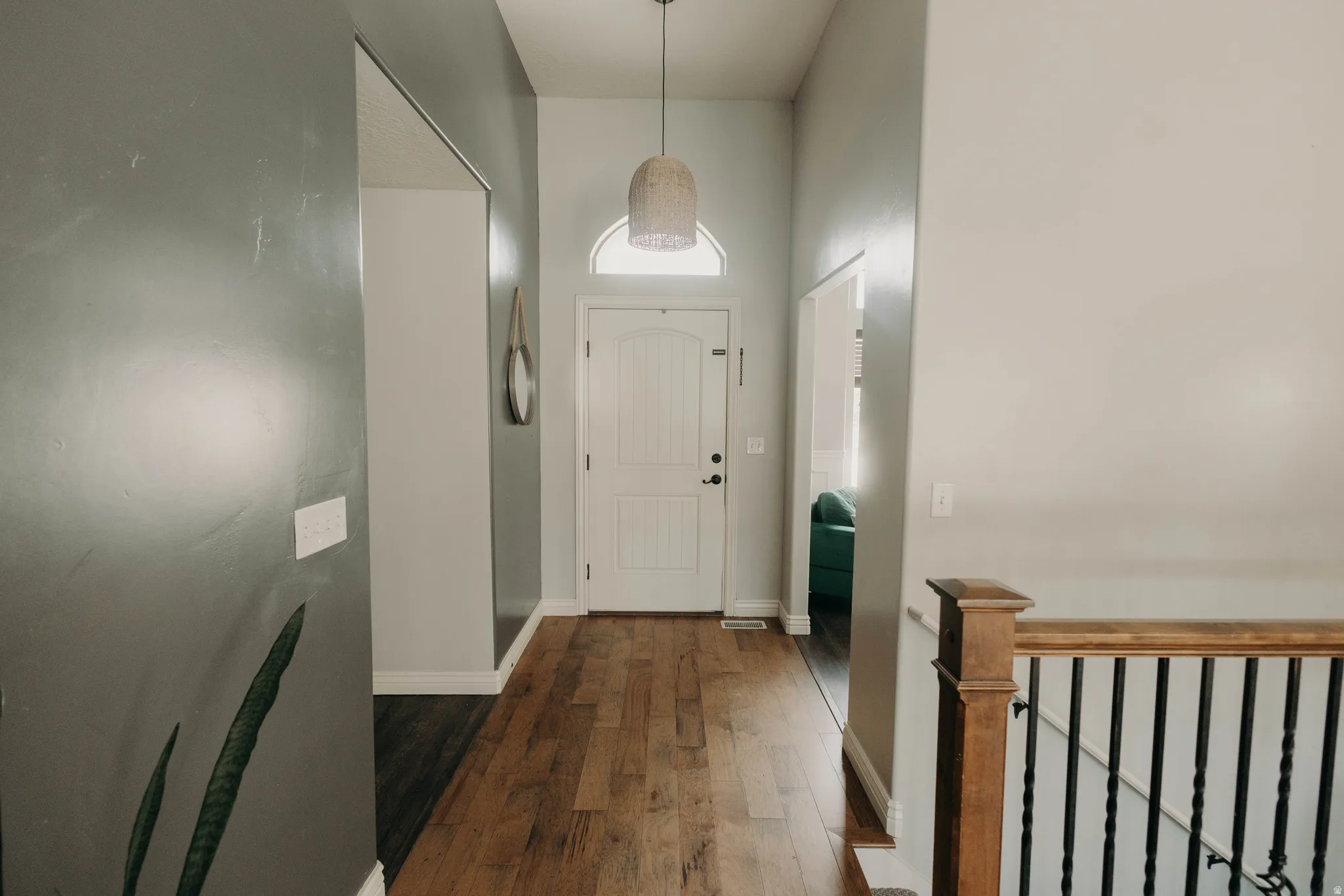 Entryway featuring wood-finish flooring, a white paneled door with an arched transom, and a contemporary pendant light fixture