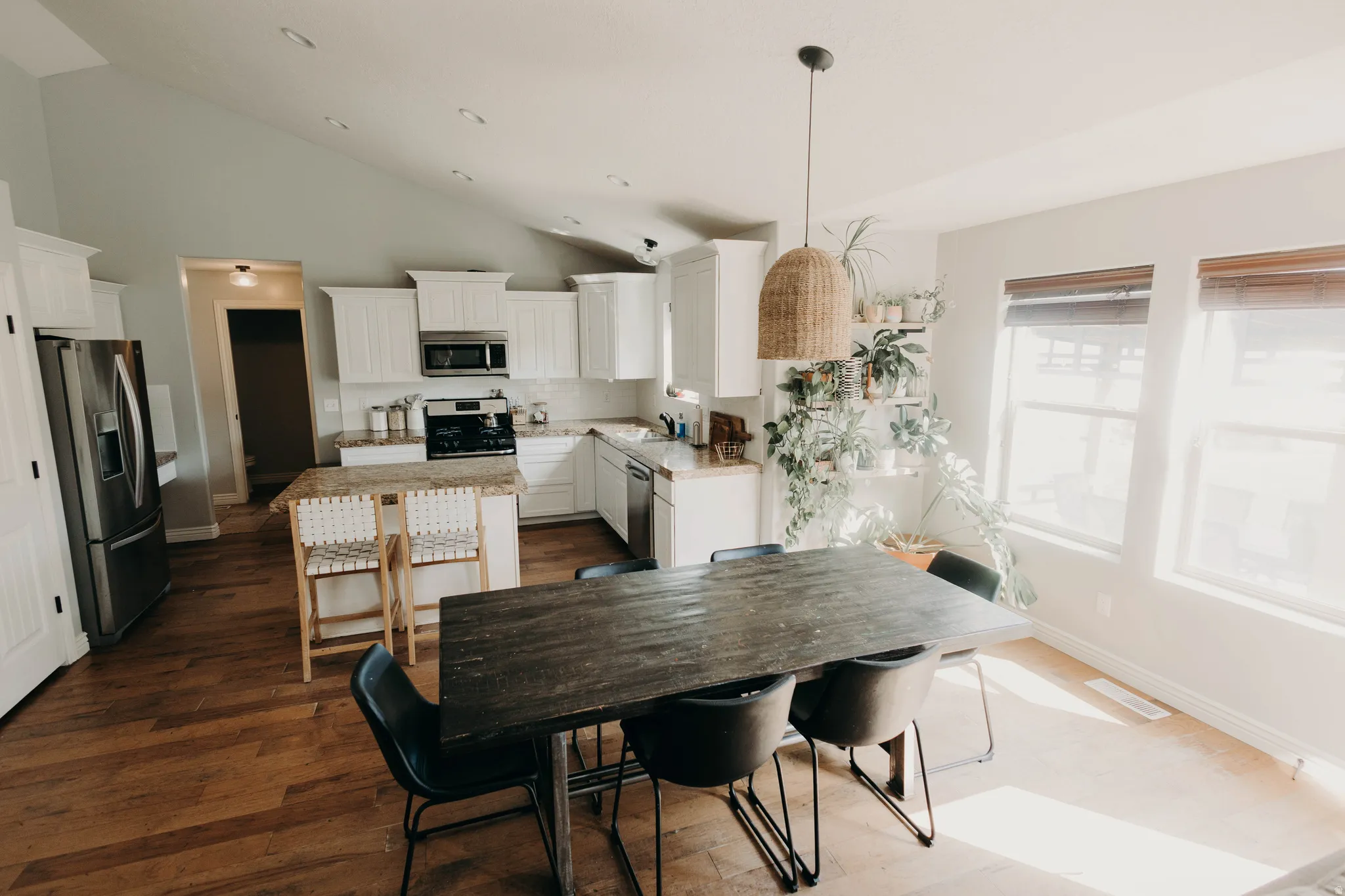 Open-concept kitchen and dining area featuring wood-finish flooring, white cabinetry, and stainless steel appliances