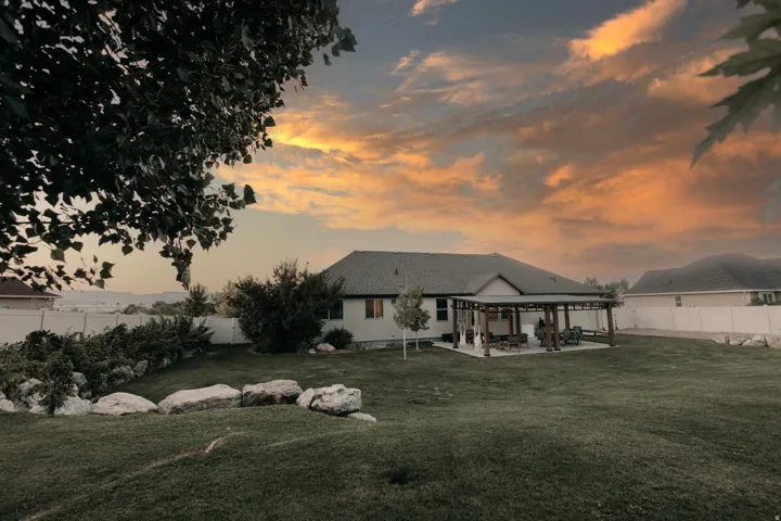 Expansive backyard featuring a large lawn, a paved patio with a pergola, and established perimeter landscaping