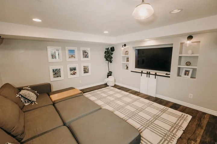 Entertainment area featuring a built-in media center with shelving, recessed lighting, and wood-finish flooring