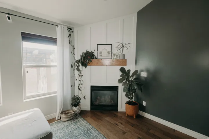 Corner fireplace featuring a wood mantel, white board and batten wall treatment, and rich wood-finish flooring