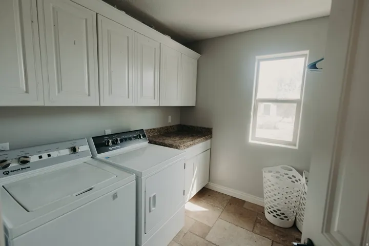 Laundry room featuring upper and lower cabinetry, granite-finish countertop, and tiled flooring