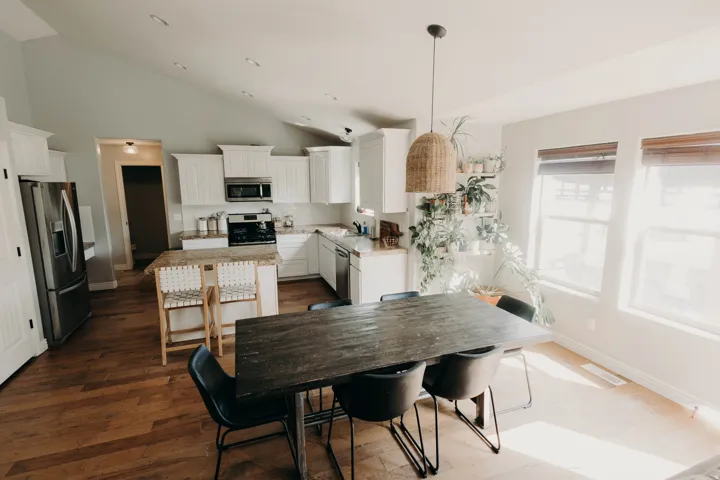 Open-concept kitchen and dining area featuring wood-finish flooring, white cabinetry, and stainless steel appliances