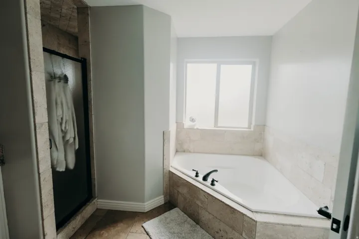 Corner soaking tub with dark-finish fixtures and frosted window