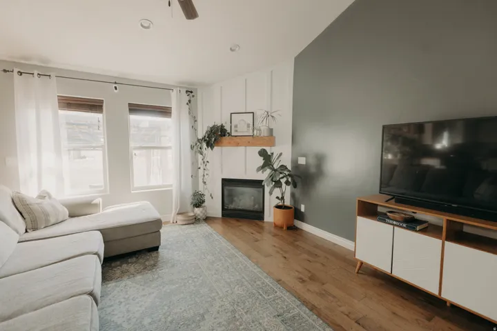 Living area featuring wood-finish flooring, a fireplace with a wood mantel, and a ceiling fan