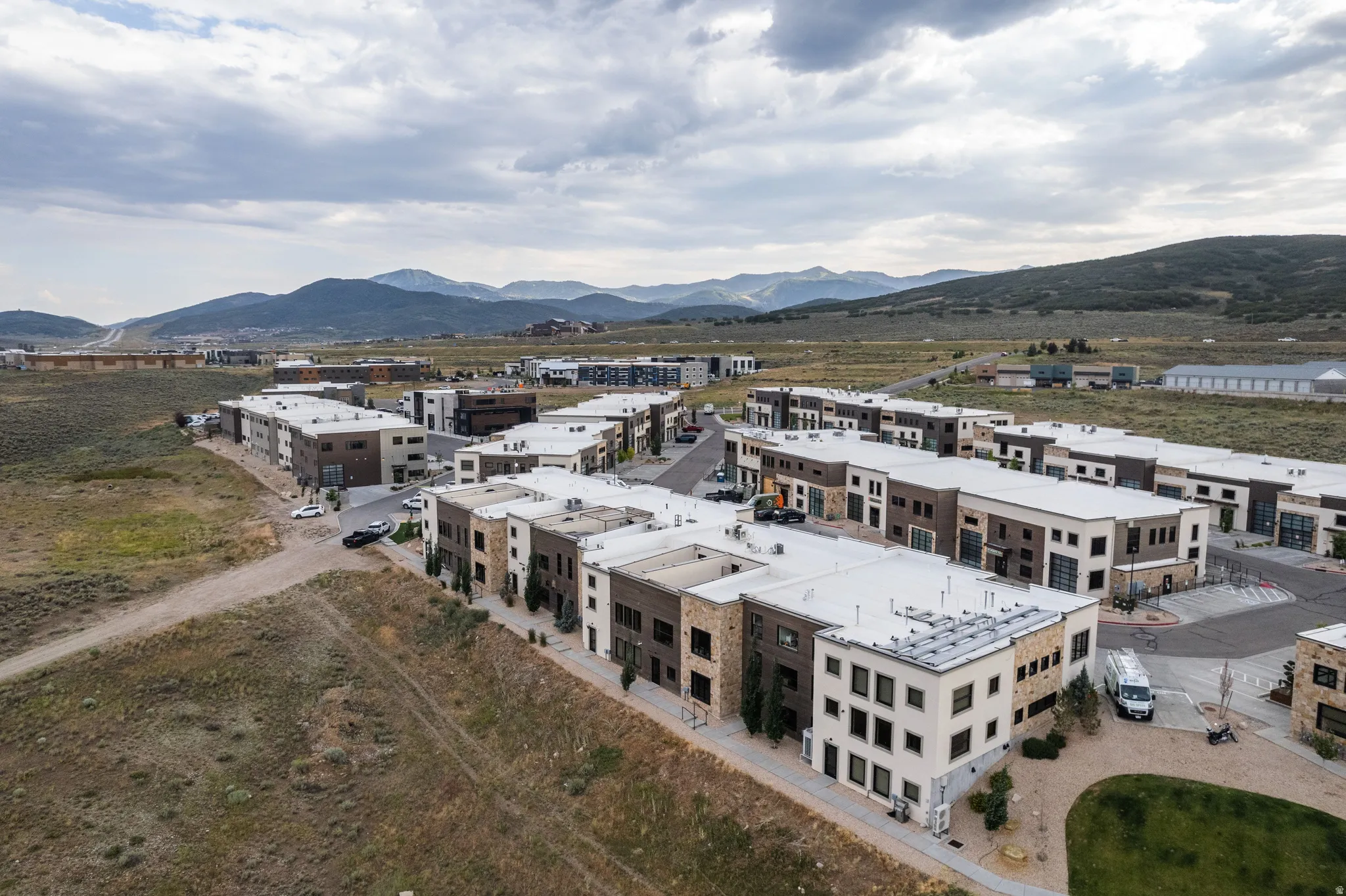Modern multi-level townhome-style residences featuring varied facades with stone and panel accents, flat roofs, and integrated garages