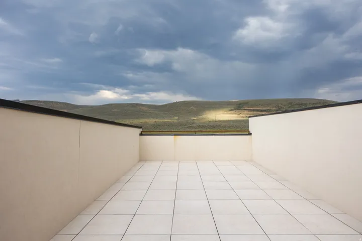 Rooftop terrace with light-toned rectangular tile flooring and low perimeter walls