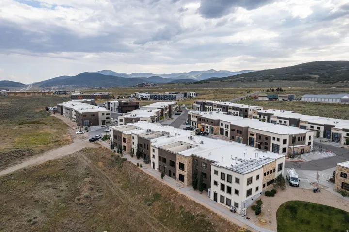 Modern multi-level townhome-style residences featuring varied facades with stone and panel accents, flat roofs, and integrated garages