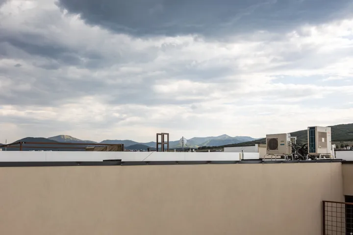 Rooftop terrace with stucco parapet, showcasing distant mountains and open sky
