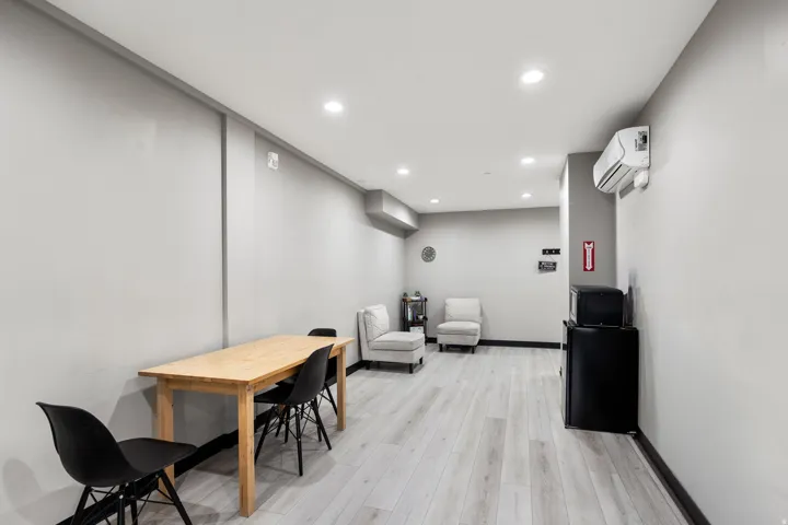 Spacious room featuring light wood-finish flooring, recessed lighting, and a wall-mounted air conditioning unit