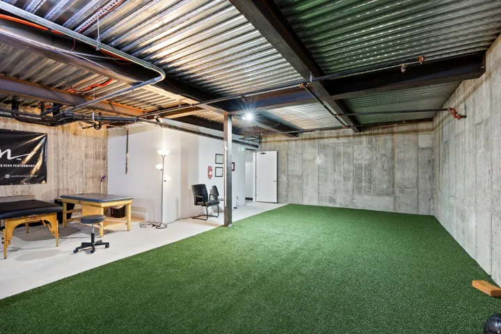 Expansive basement area featuring an artificial turf surface and exposed corrugated metal ceiling