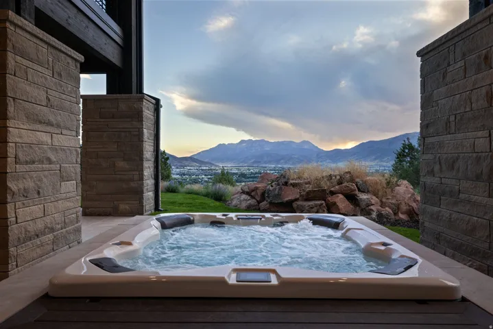 Outdoor hot tub with textured stone columns and a wood-finish deck
