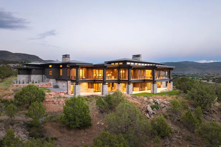 Contemporary multi-level residence featuring expansive window walls, stone accents, and multiple outdoor patio areas