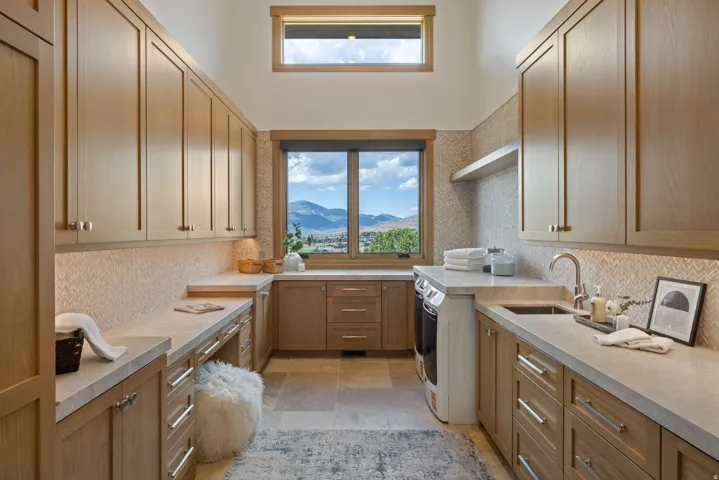 Spacious utility room featuring extensive built-in cabinetry, durable countertops, and a window framing mountainous scenery