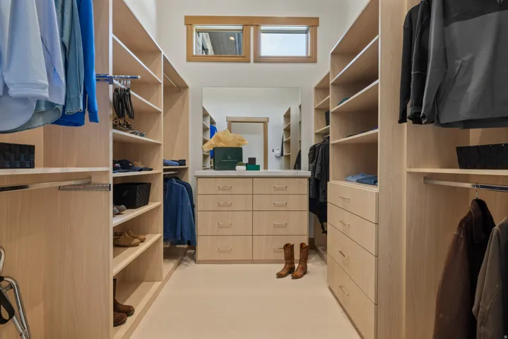Spacious walk-in closet featuring extensive built-in shelving and hanging rods