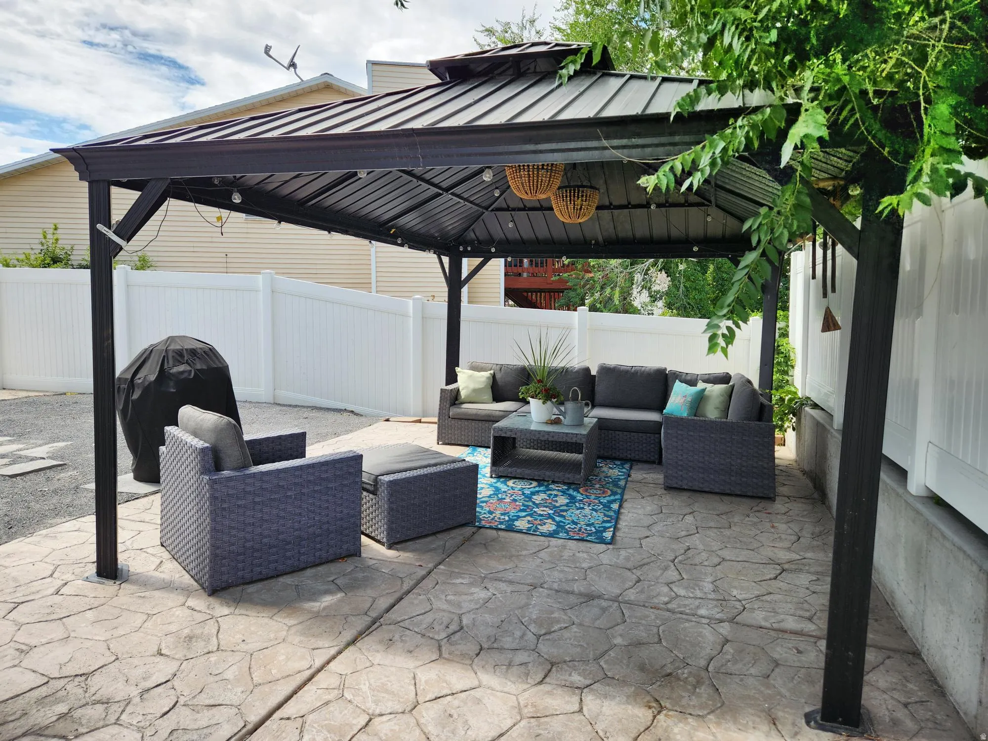 Stamped concrete patio under a dark metal gazebo with lights and Barbeque
