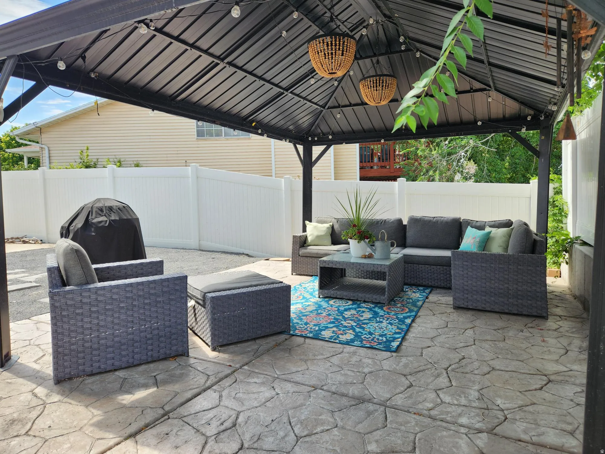 Covered patio area featuring a stamped concrete surface and a white privacy fence