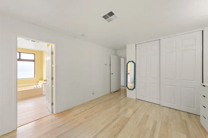 Bright room with light wood-finish flooring, white walls, and sliding panel closet doors