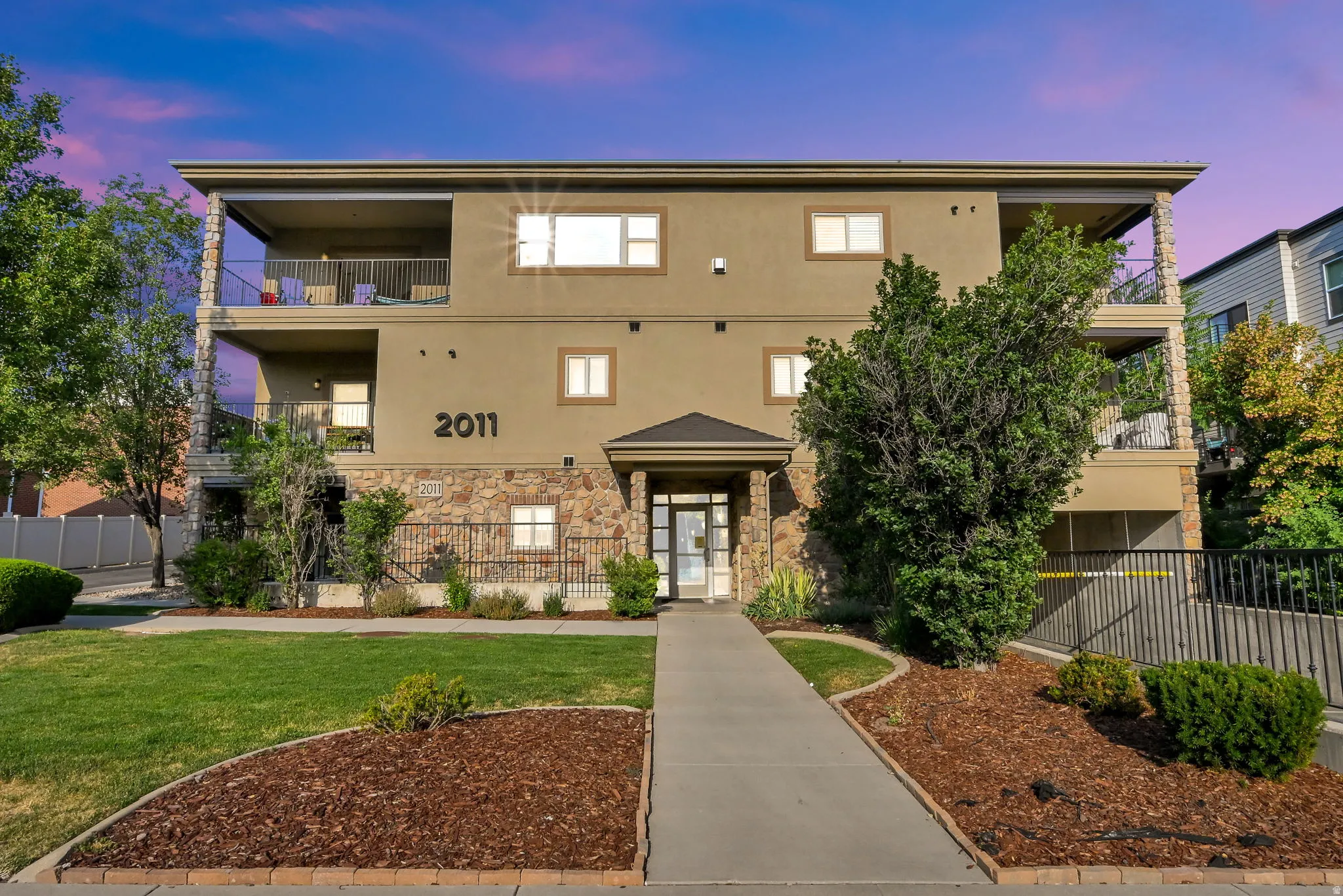 Entrance from 2100 East: Multi-story residential building featuring a stone and stucco facade