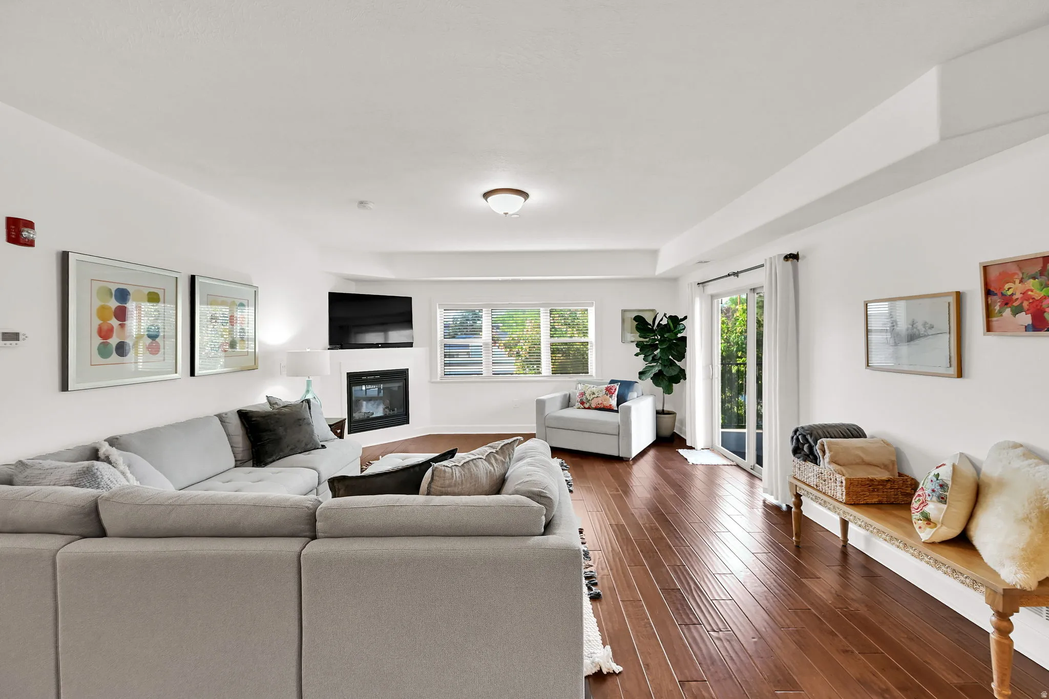 Spacious living area featuring wood-finish flooring, a corner fireplace, and multiple windows