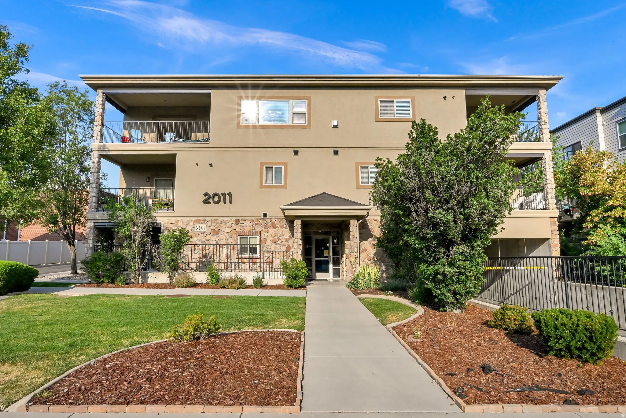 Multi-story building featuring a stucco exterior with stone accents and multiple private balconies