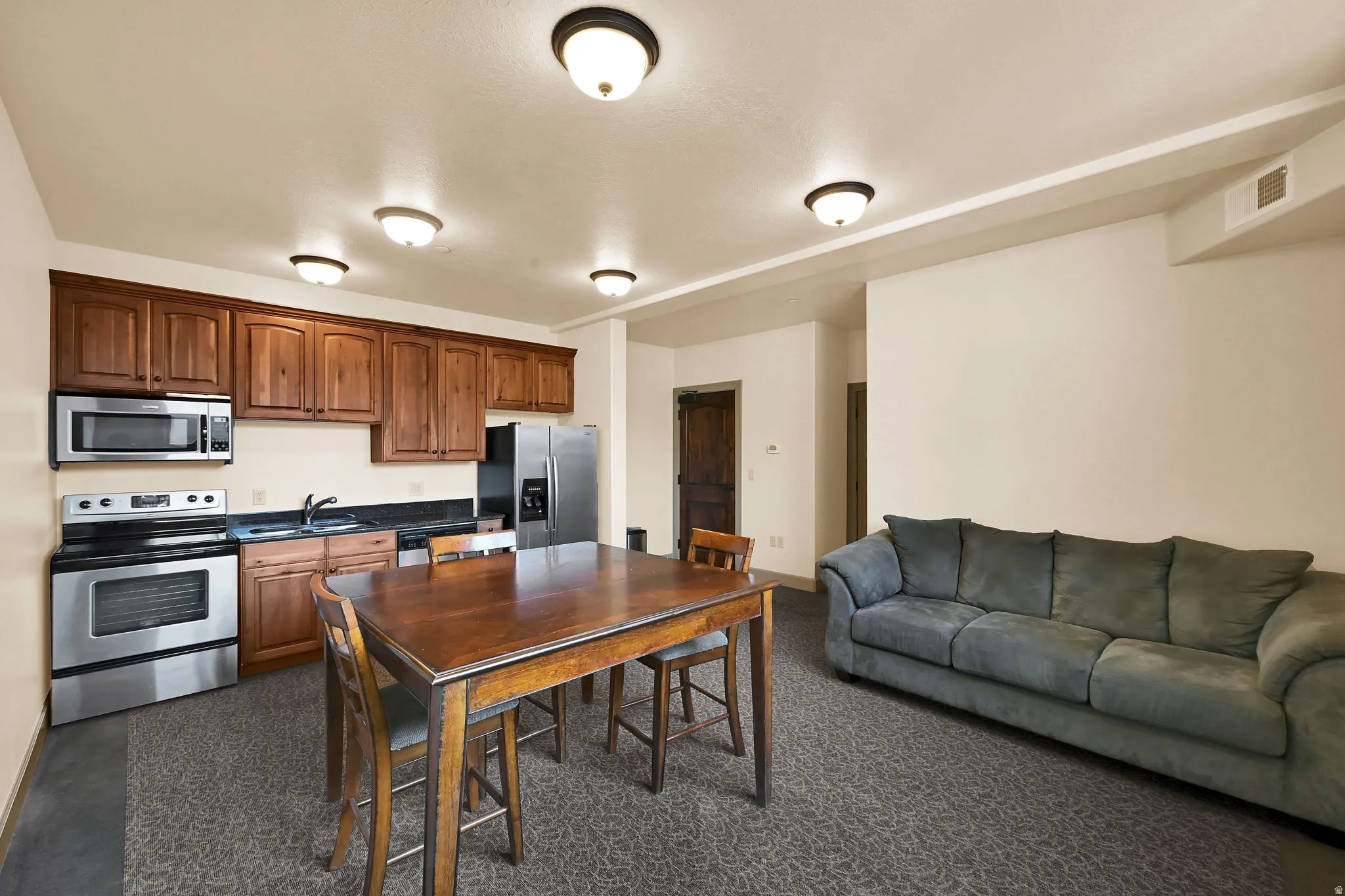 Community Room on Level V: 200 (View) Kitchenette featuring warm wood cabinetry, stainless steel appliances, and dark countertops