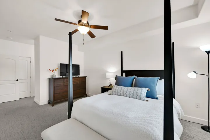Primary Bedroom: Spacious bedroom featuring light-toned carpeting, a ceiling fan with integrated lighting, and a tray ceiling detail