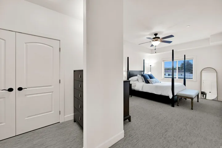 Primary Bedroom: Bright bedroom featuring a tray ceiling with a built-in ceiling fan, two closets, and a large window with blinds