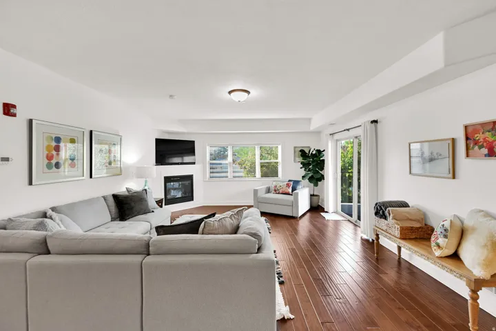 Spacious living area featuring wood-finish flooring, a corner fireplace, and multiple windows