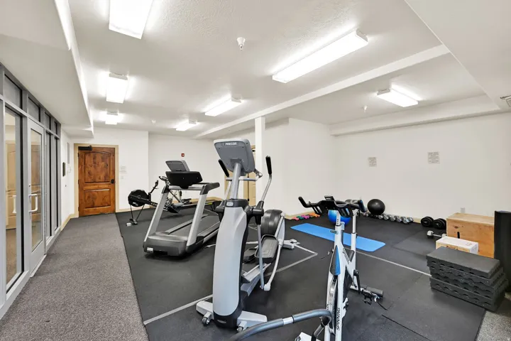 Dedicated fitness space featuring rubber flooring, extensive recessed and surface-mounted lighting