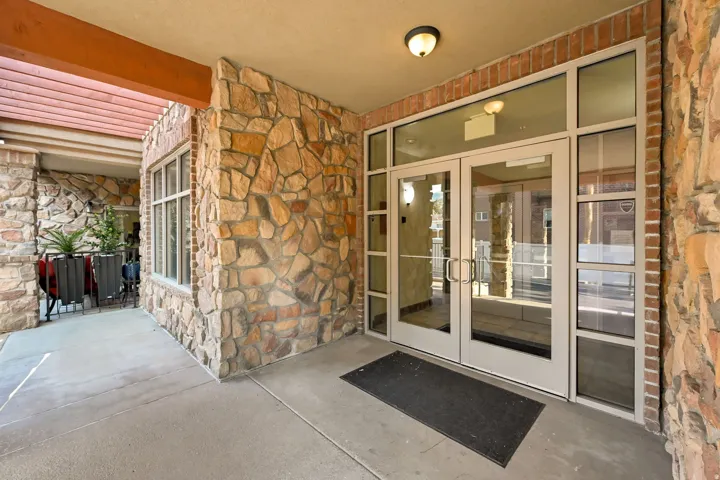 Main Entry Doors: Stone veneer exterior featuring a covered entry, glass double doors, and transom windows
