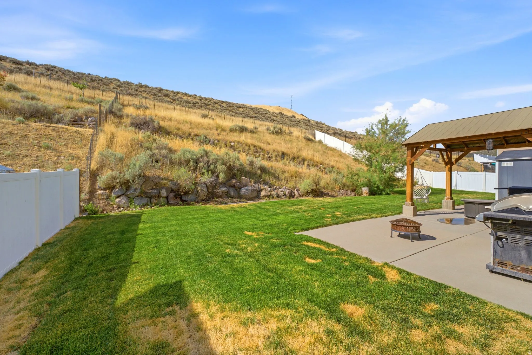 Expansive backyard featuring a lush lawn, concrete patio, and a covered pergola