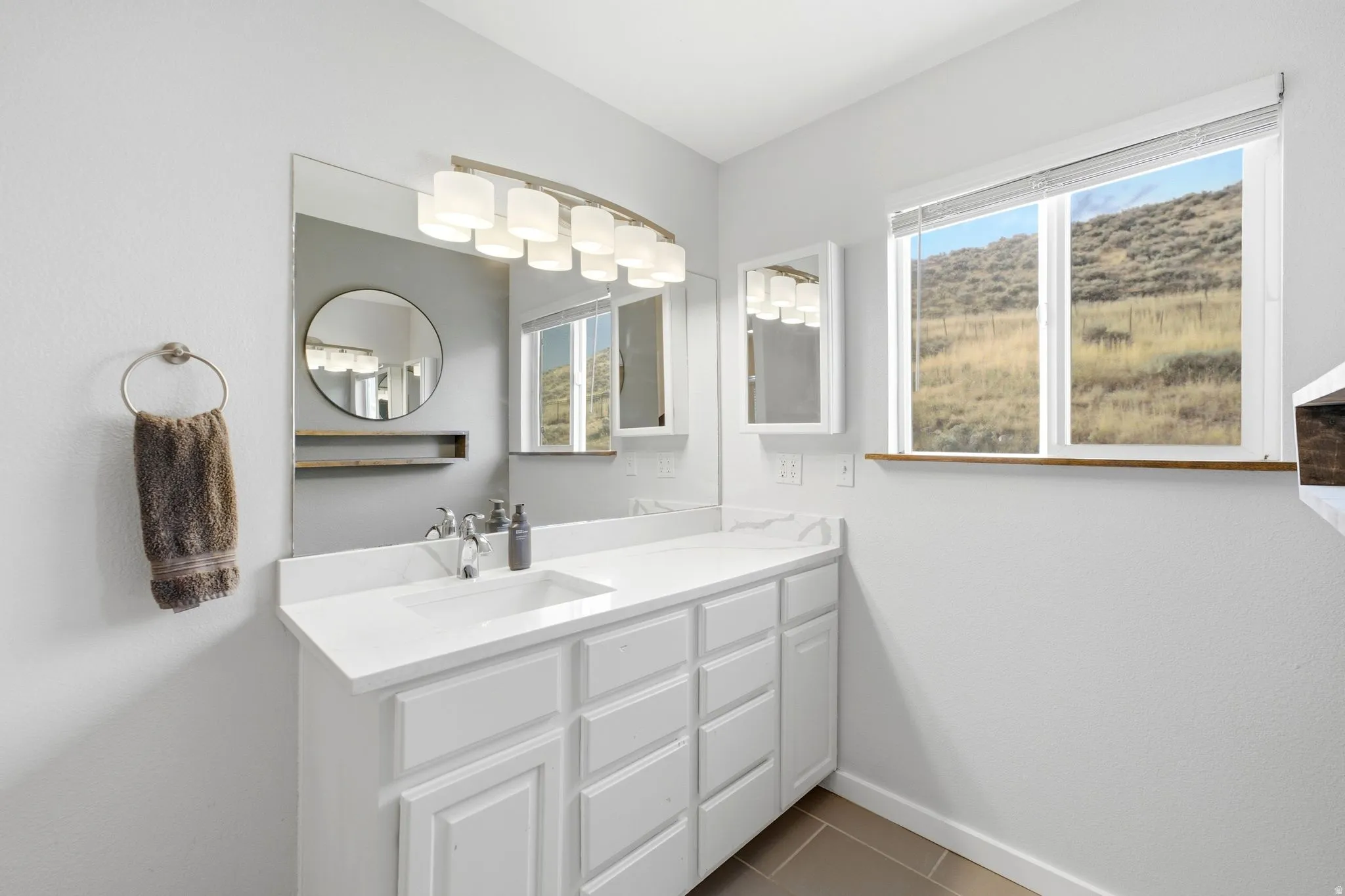 White vanity with a single basin, undermount sink, and a countertop featuring a subtle veining pattern
