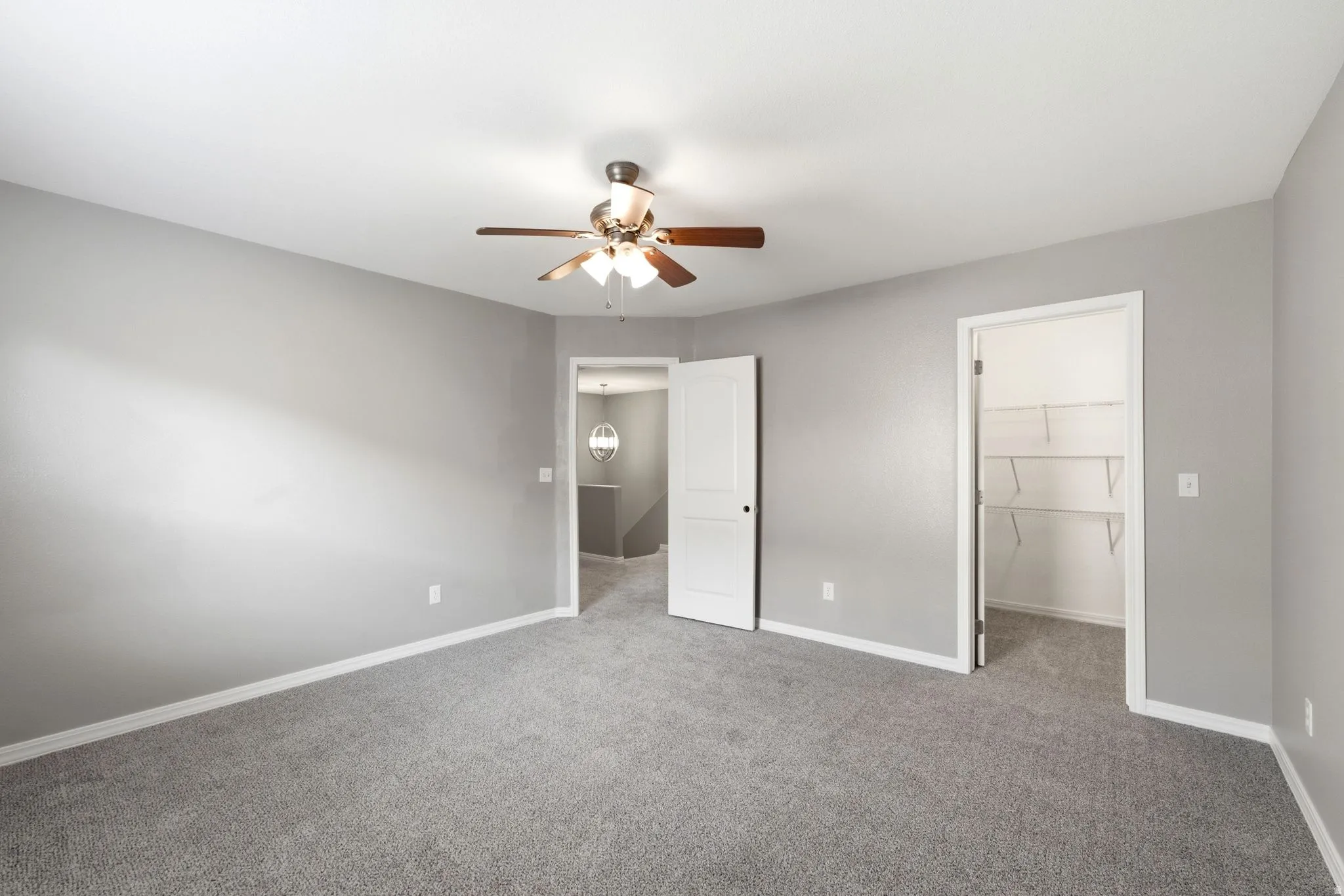 Spacious room featuring neutral grey walls and coordinating grey carpet flooring