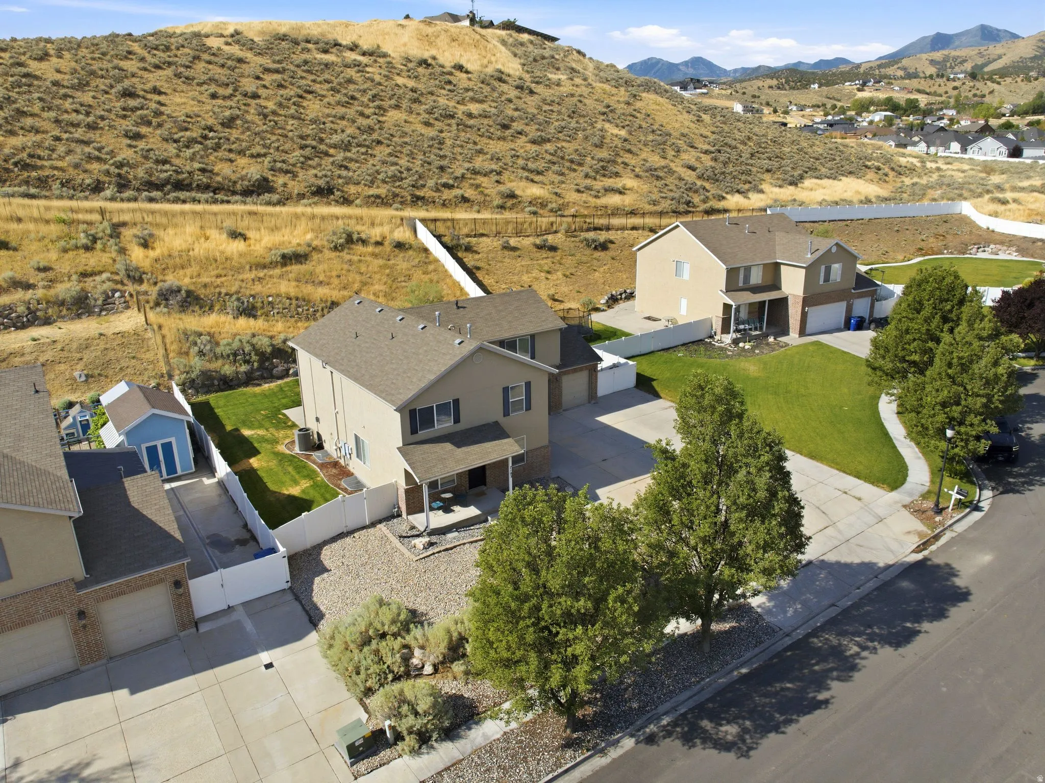 Two-story residence featuring a three-car garage, covered porch, and fenced backyard with a shed