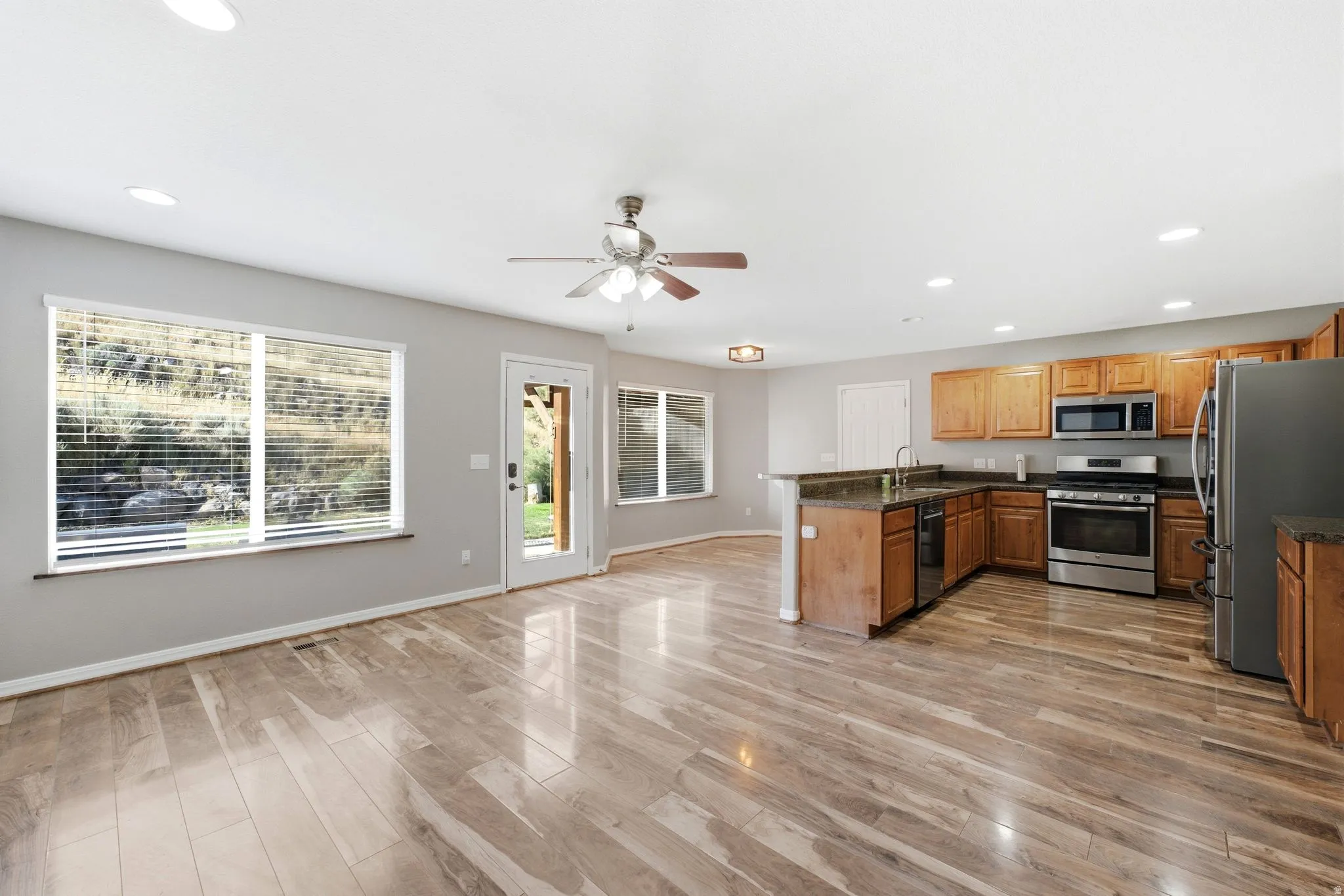 Open-concept living area featuring wood-finish flooring, recessed lighting, and a ceiling fan
