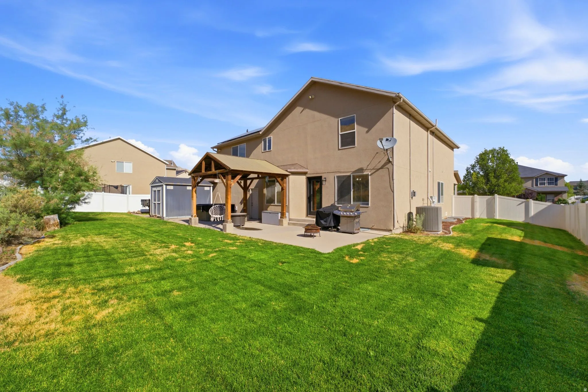 Expansive backyard featuring a manicured lawn, a concrete patio, and a covered pergola