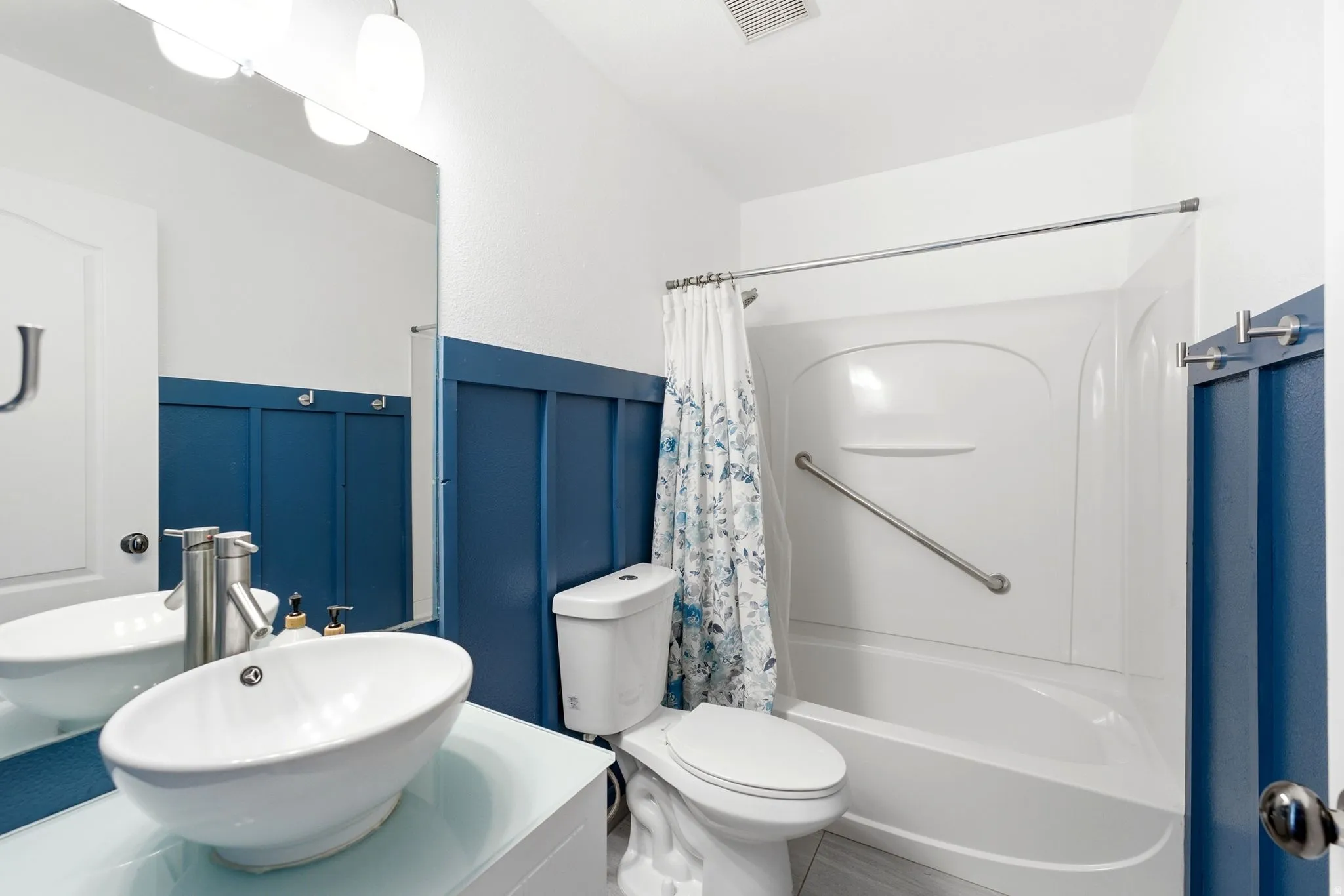 Bathroom featuring a vessel sink with a brushed nickel faucet, a full vanity mirror, and modern overhead lighting