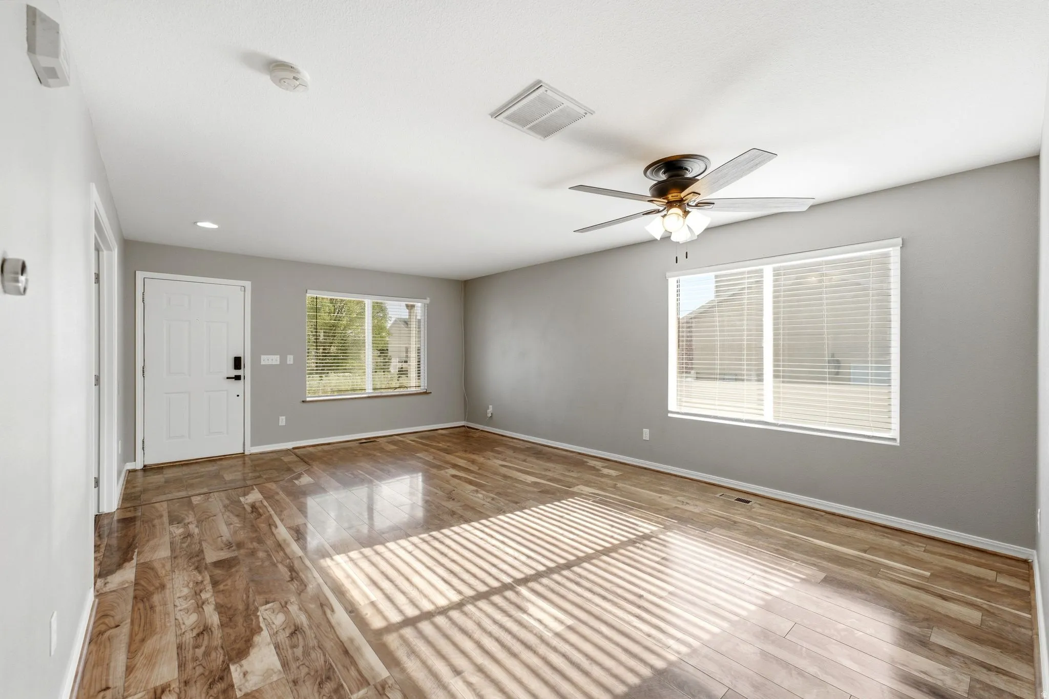 Spacious room featuring wood-finish flooring, light grey walls, and a white ceiling